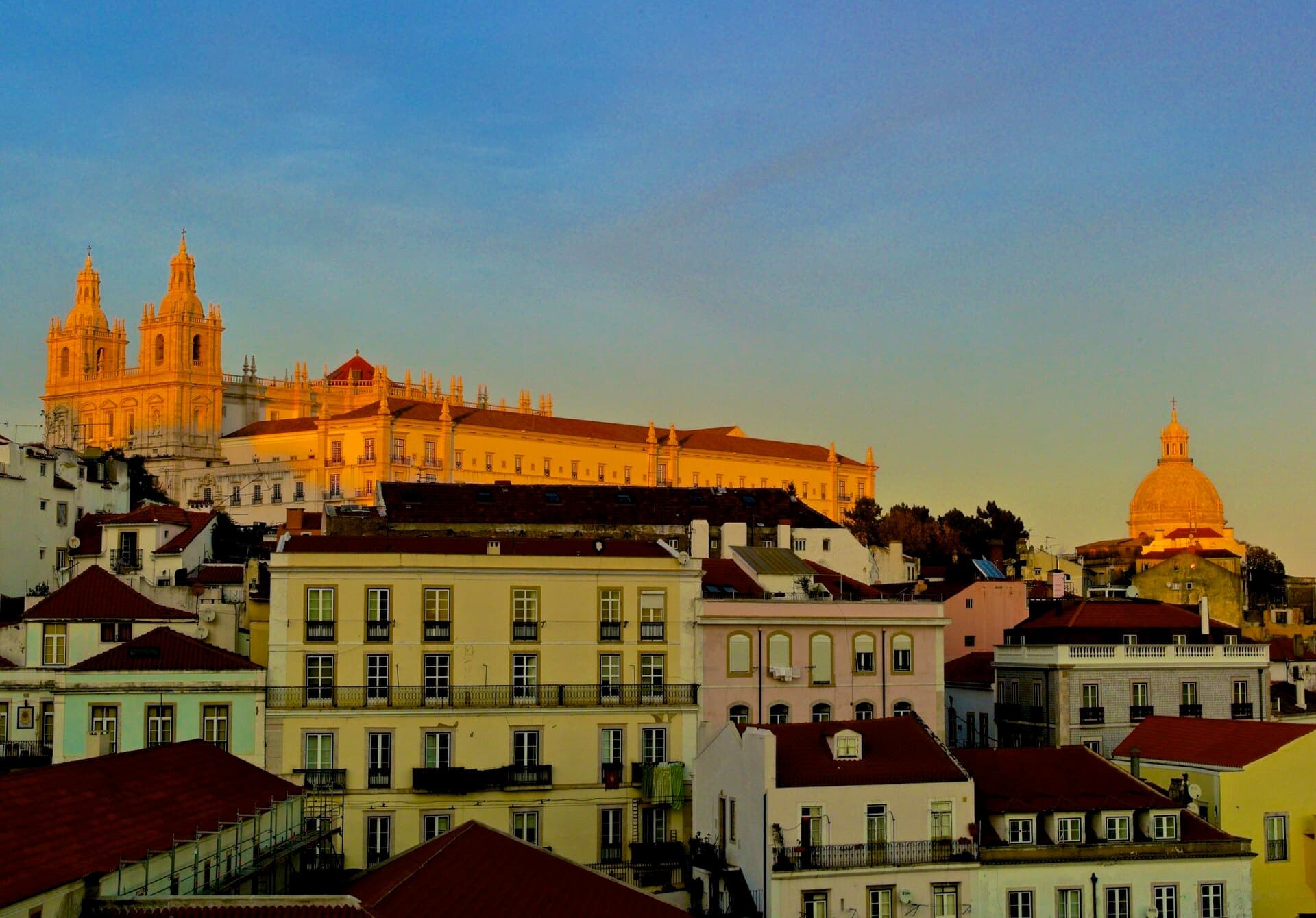 Alfama rooftops and the São Vicente de Fora monastery glowing amber at the end of the day in Lisbon